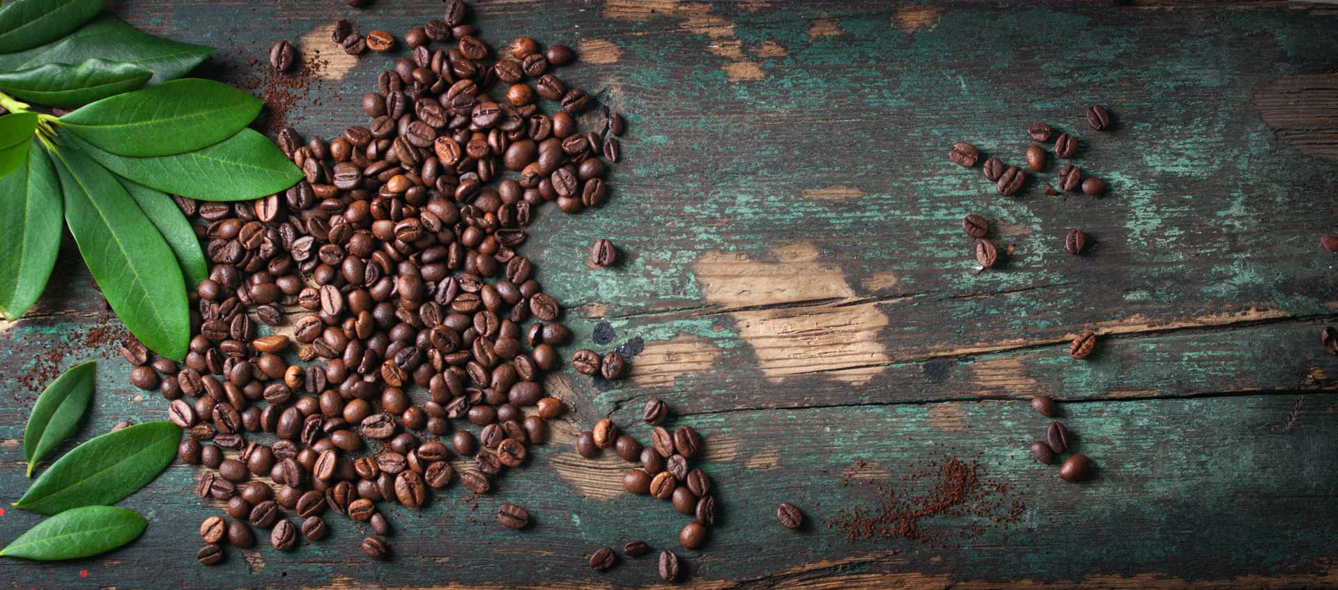 Utspridda kaffebönor på slitet träunderlag